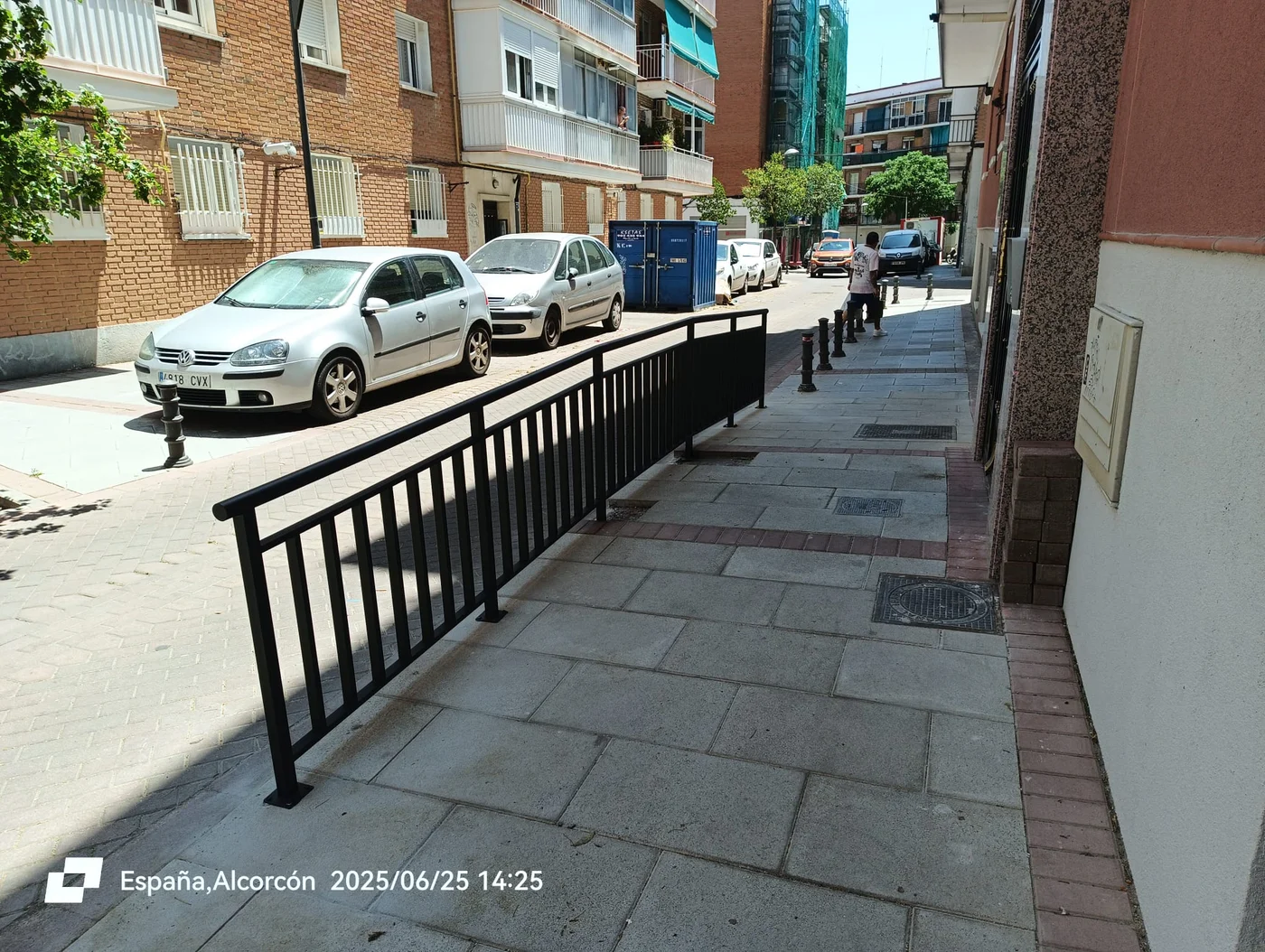 Barandilla perimetral de barrotes metálicos en negro instalada en acera con rampa peatonal exterior en Alcorcón