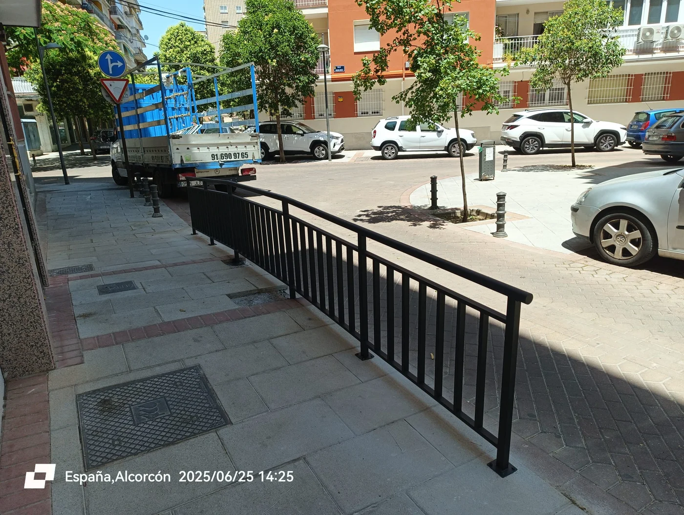 Barandilla de protección peatonal en acero lacado negro instalada en acera urbana en Alcorcón